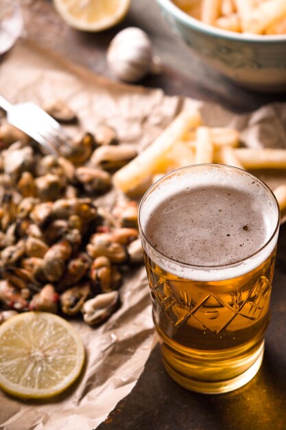 Un verre de bière avec des moules floues et des frites verticales