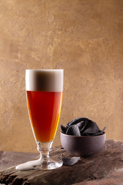 Photo un verre de bière avec de la mousse se dresse sur une planche de bois