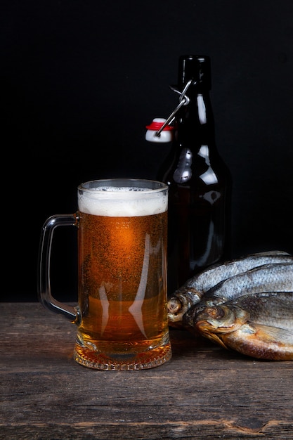 Verre de bière, poisson sec et bouteille de bière sur fond noir