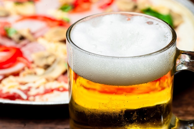 Verre de bière se bouchent sur fond de pizza.