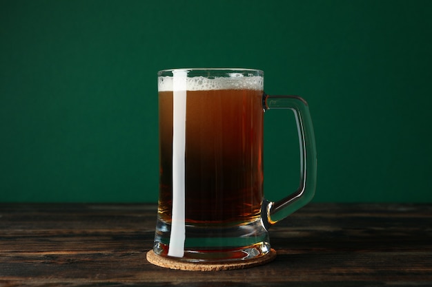 Verre de bière sur table en bois sur fond vert