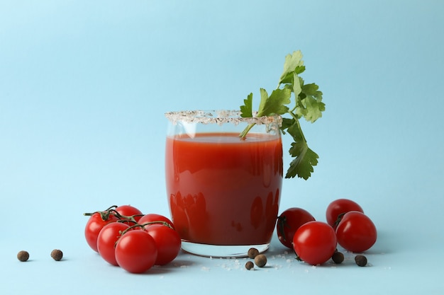 Verre de Bloody Mary et tomates sur fond bleu