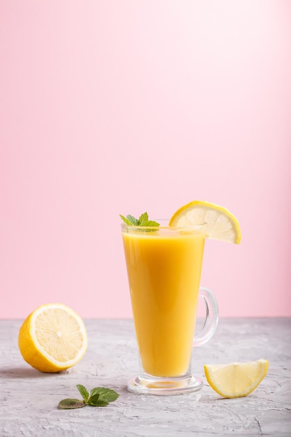 Verre de boisson au citron sur fond gris et rose. Morning, printemps, concept de boisson saine. Vue latérale, copiez l'espace.