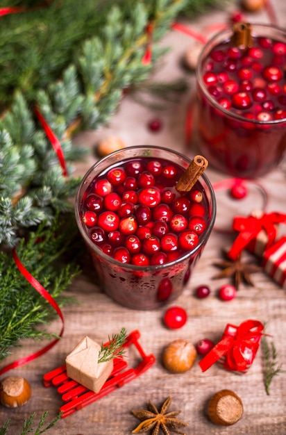 Verre de boisson aux canneberges, canneberges, bâtons de cannelle, étoiles d'anis sur un fond en bois. Boissons d'hiver de Noël.