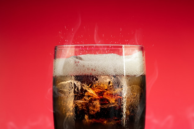 Verre à boisson gazeuse avec éclaboussures de glace. Verre Cola avec rafraîchissement estival.