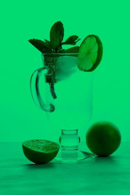 Verre de boisson gazeuse avec des tranches de citron vert et de menthe sur un fond coloré Concept de boisson froide d'été Gros plan