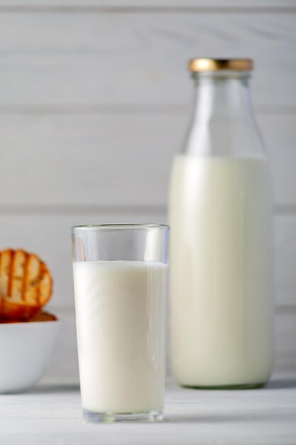 Verre et bouteille de lait sur un fond en bois blanc