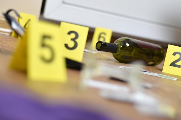 Photo un verre brisé et une bouteille de vin marqués comme preuves lors de l'enquête sur la scène du crime.