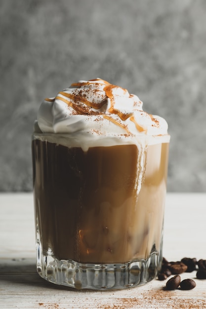 Verre de café glacé à la crème versée sur table en bois