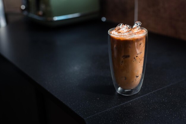 Un verre de café glacé avec du lait sur la table.