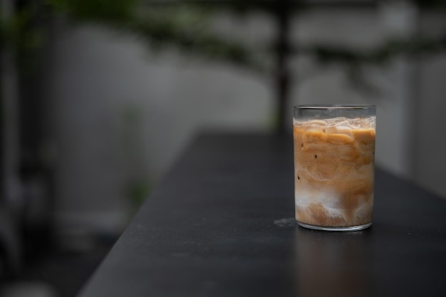 Un verre de café glacé est posé sur une table noire.