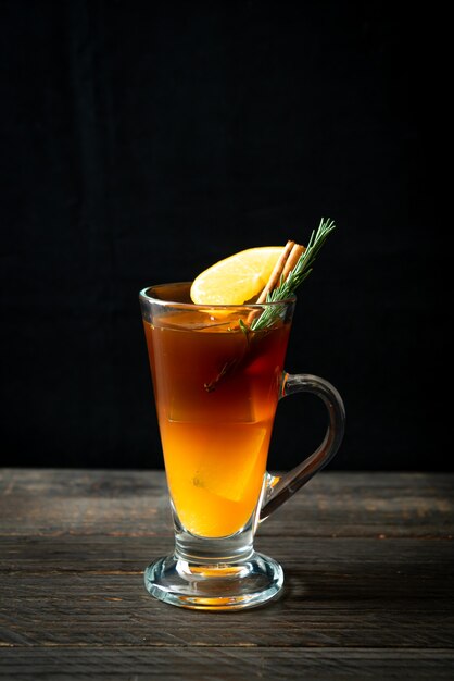 Un verre de café noir américain glacé et une couche de jus d'orange et de citron décoré de romarin et de cannelle