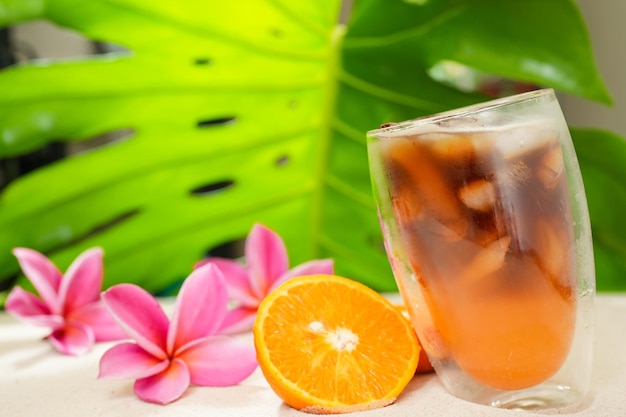 Verre de café à l'orange glacé et demi-mandarine coupée sur le sable