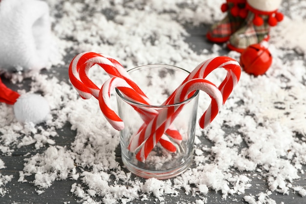 Verre avec des cannes de Noël et de la neige sur la table