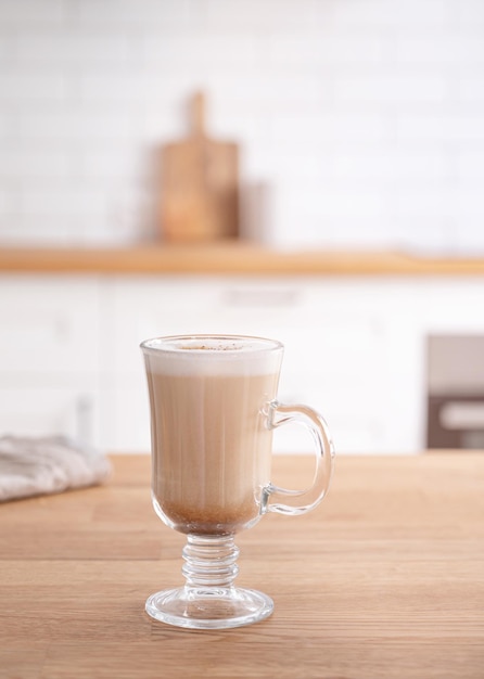 Verre De Cappuccino Parfumé à La Cannelle Sur Une Table En Bois Dans Le Contexte D'une Cuisine Blanche Tôt Le Matin Concept De Petit-déjeuner Vue De Face