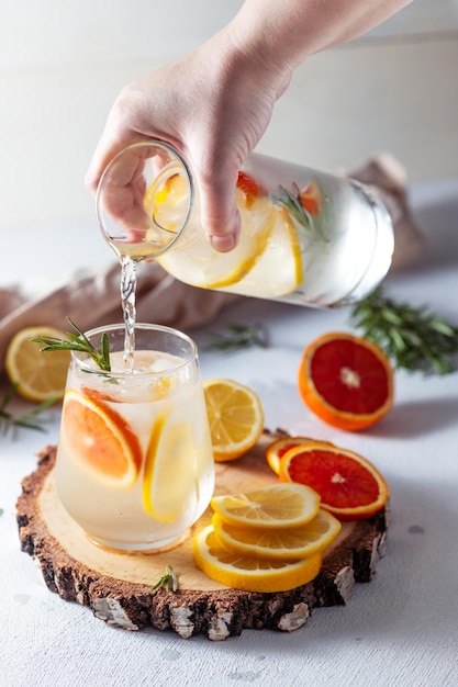 Un verre et une carafe de limonade Tranches de citron et de pamplemousse avec des feuilles de romarin dans une boisson