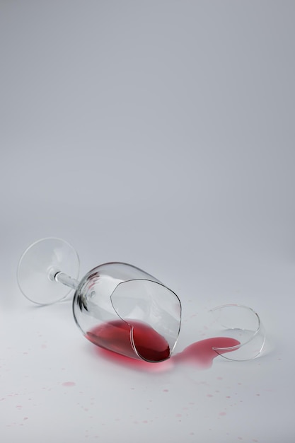 Verre cassé avec du vin renversé sur fond clair