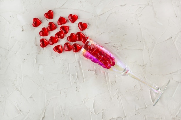 Verre à champagne avec des éclaboussures de coeur rouge sur fond blanc. Vue de dessus, copiez l'espace. Concept de la Saint-Valentin