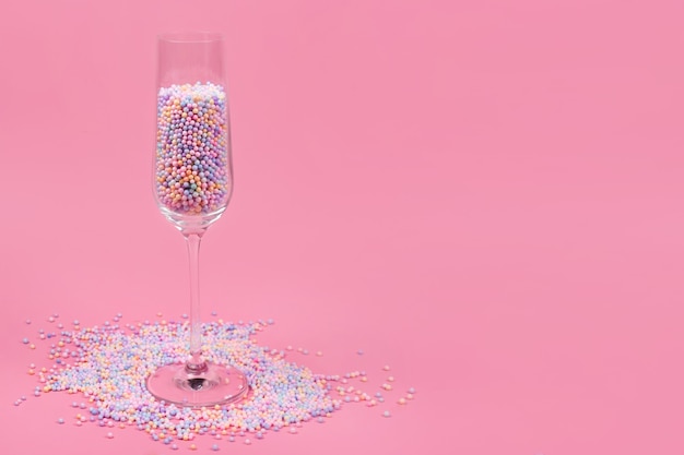 Verre à champagne rempli de boules de sucre colorées sur rose
