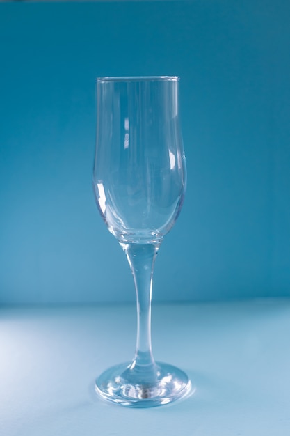 Un verre de champagne vide se dresse sur un fond bleu.