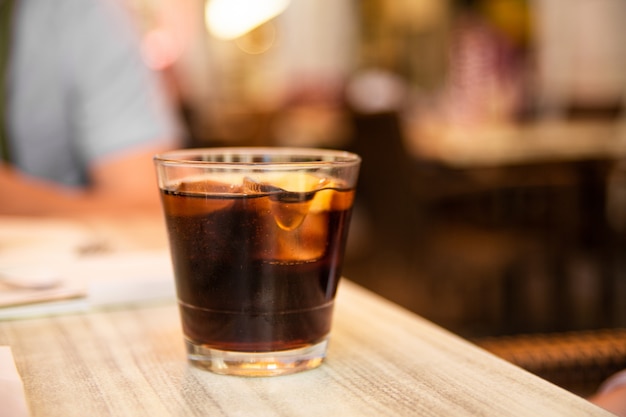 Verre de coca avec glace et citron sur la table. Café de rue. Mise au point douce.