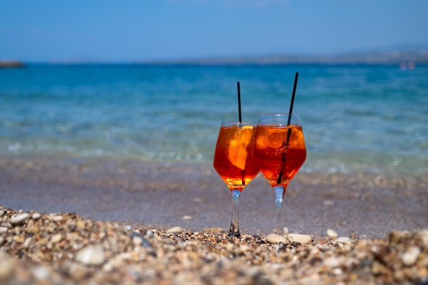 Verre de cocktail aperol spritz se dresse sur le sable près de la mer