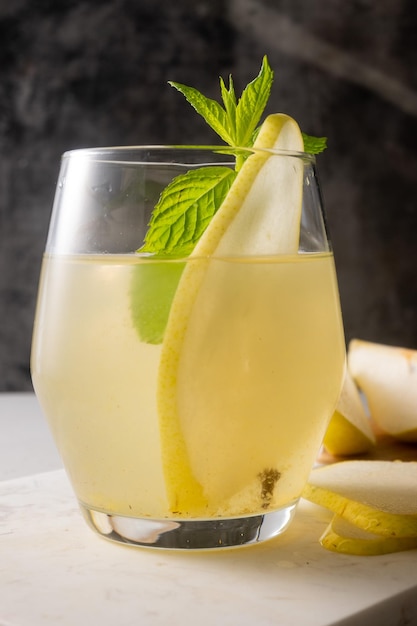 Un verre de cocktail au cidre de pomme avec une tranche de menthe sur le bord.