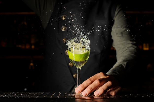 Verre à cocktail avec boisson alcoolisée éclaboussante et citron vert