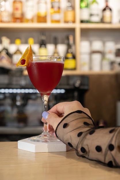 Un verre de cocktail de canneberges et une main féminine sur le fond du bar.