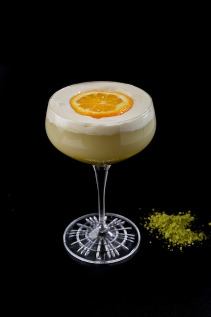 Verre à cocktail crémeux avec tranche de crème et orange et wasabi sur fond noir