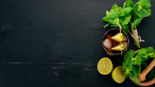 Verre à cocktail Cuba libre Lime menthe Sur un fond en bois noir Espace libre pour le texte