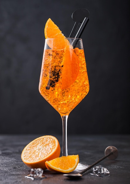 Verre de cocktail d'été aperol spritz avec des tranches d'orange et une cuillère de bar sur fond noir avec des glaçons