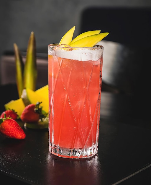 Un verre de cocktail à la fraise avec une paille à côté et une fraise à côté.