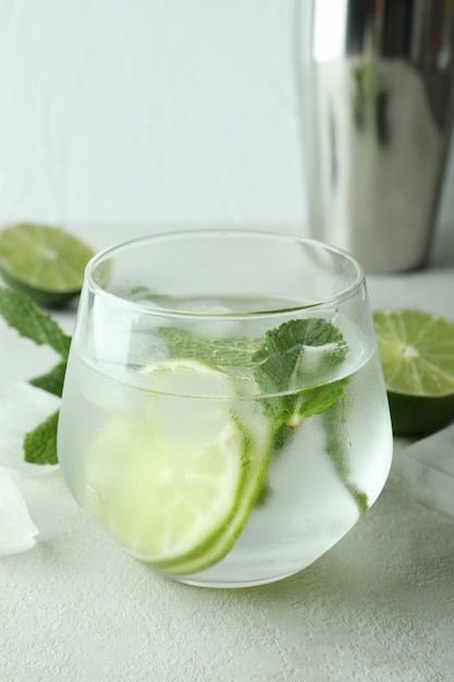 Verre de cocktail mojito et ingrédients sur table texturée blanche