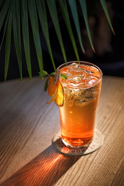 Un verre de cocktail orange avec de la glace et une feuille sur le côté