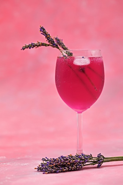 Un verre de cocktail rose et de lavande sur un fond magenta dégradé