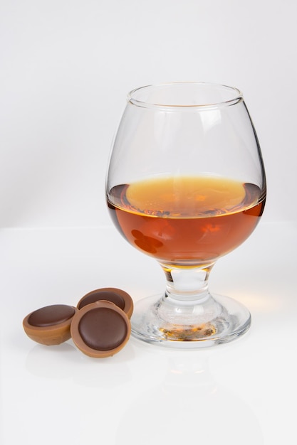 Photo verre à cognac et chocolat sur fond blanc