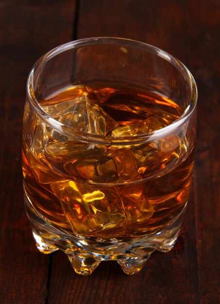 Verre de cognac avec de la glace sur fond de bois