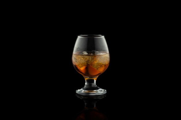 Photo verre de cognac avec de la glace isolé sur fond noir.