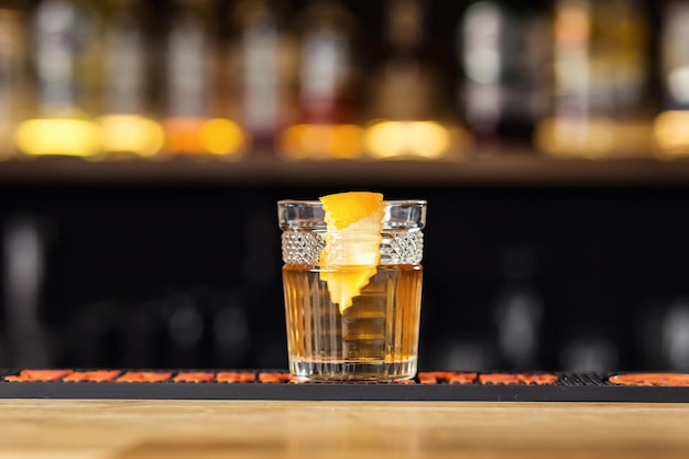 Verre de cognac de whisky ou de brandy avec du citron et des glaçons debout sur le comptoir du bar