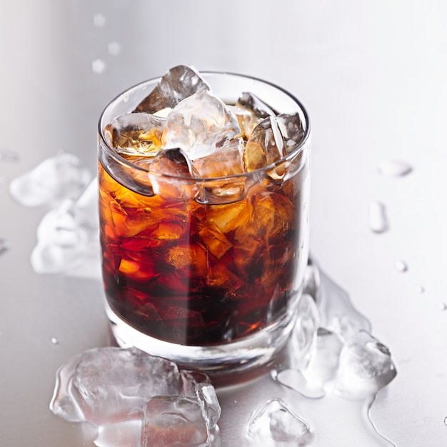 Verre de cola avec de la glace et des gouttelettes d'eau