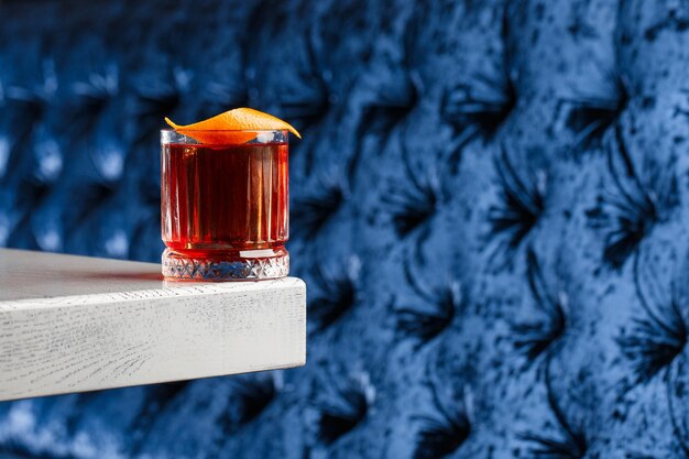 Verre en cristal avec cocktail alcoolisé froid brillant décoré de zeste d'orange Arrière-plan flou Cocktail Negroni