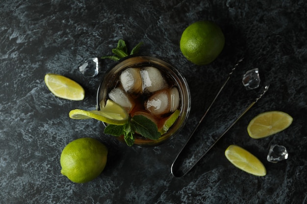 Verre de Cuba Libre et ingrédients sur une surface fumée noire