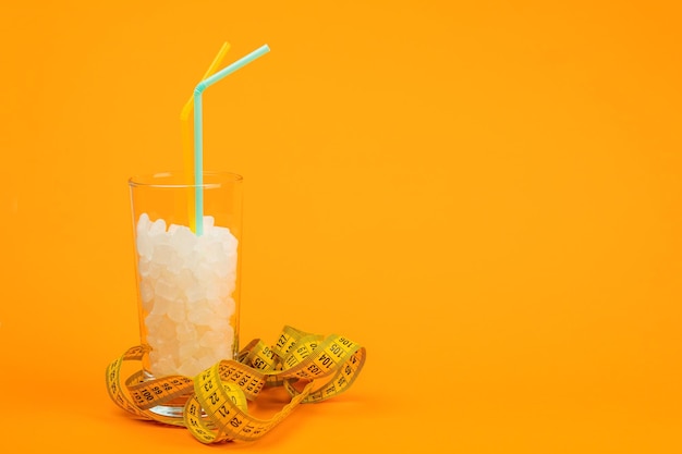 Un verre de cubes de sucre le concept de mauvaise alimentation sur fond orange