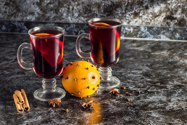 Verre de délicieux vin chaud aux oranges anis cannelle sur table sombre avec fond