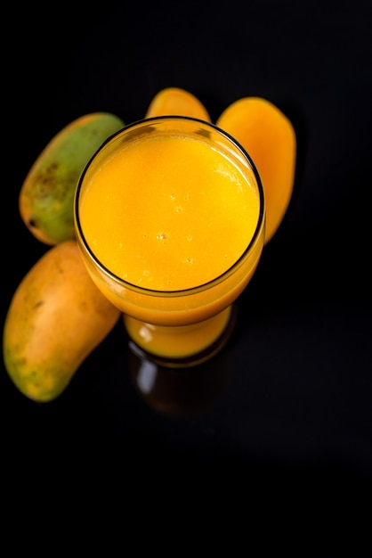 verre avec du jus de mangue sur fond noir vue du haut