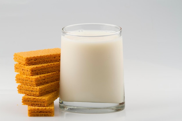 Verre avec du lait et des biscuits wafer isolés sur fond blanc