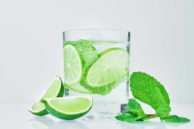 Verre d&#39;eau au citron vert et menthe sur blanc