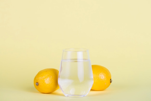 Verre d'eau aux citrons et fond jaune