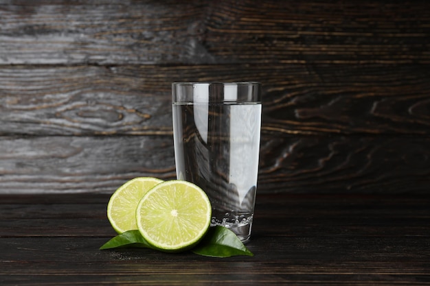 Verre d'eau citron vert et feuilles sur fond de bois